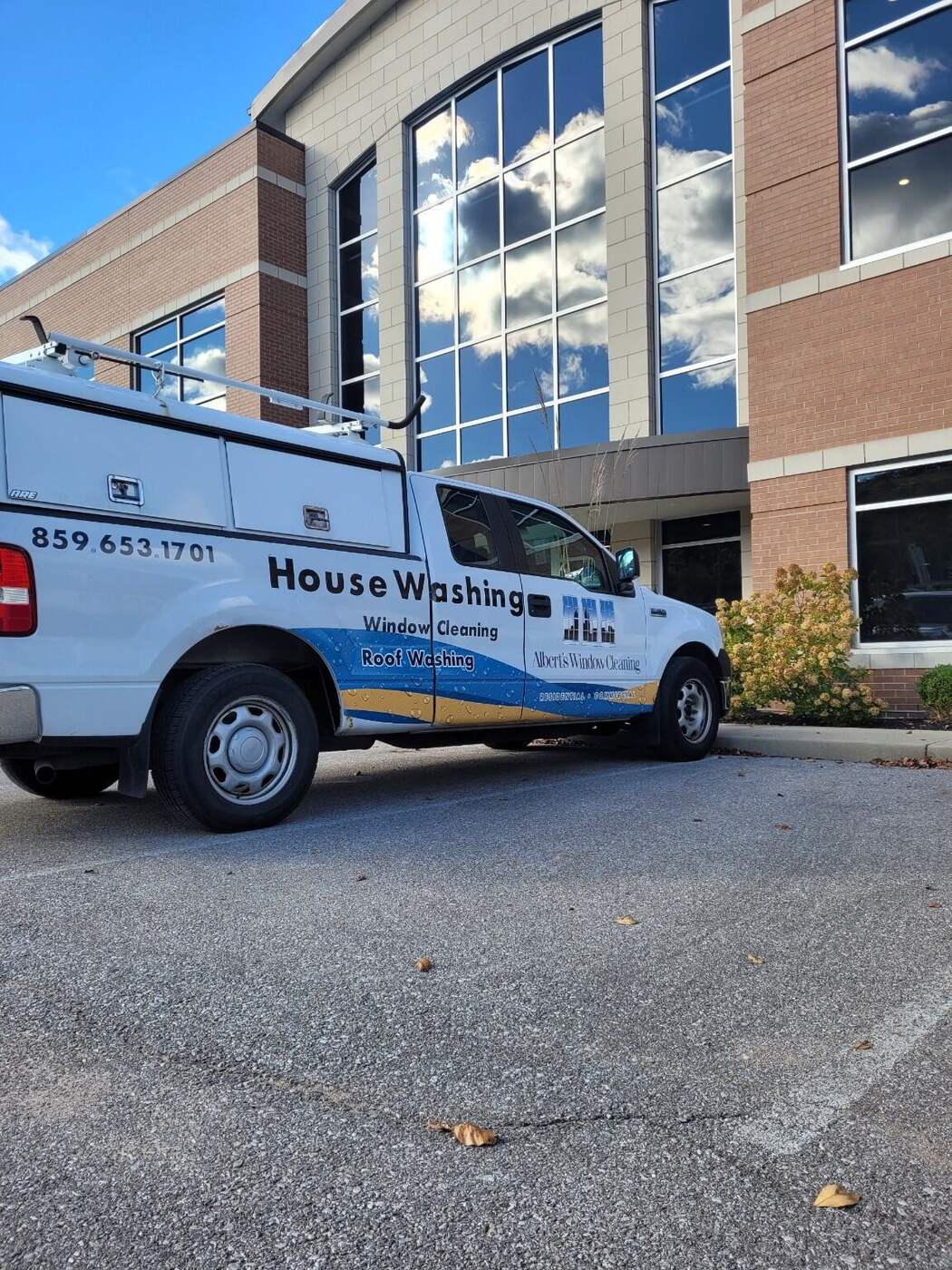 Commercial window cleaning and building service Albert's Window Cleaning truck at a commercial glass building